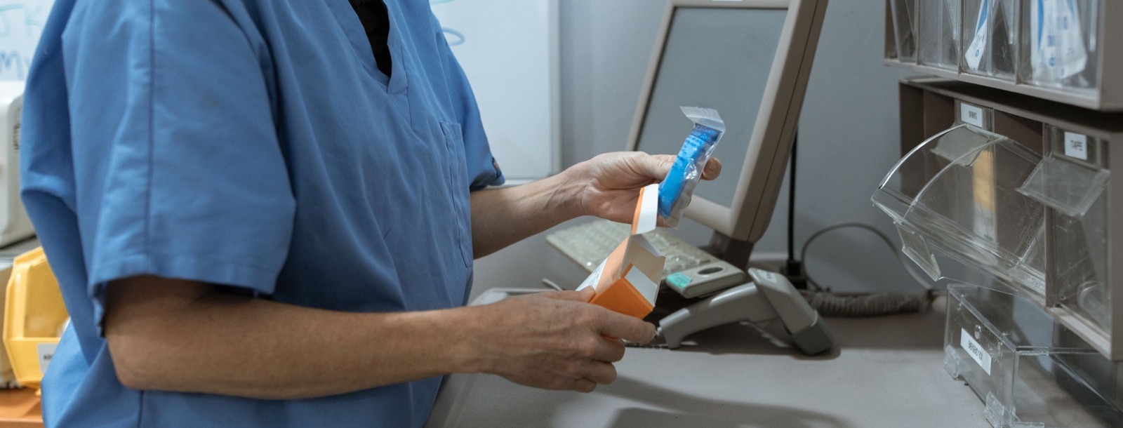 Pharmacy professional processing medication inventory at a workstation